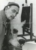 Salvador Dalí shows the set up from which he hopes to obtain the painting, a sea urchin is placed on a small chair and in its mouth, the "Aristotle's lantern", he puts a swan’s feather or other light object. The swan’s feather (he owns two swans which swim around in the sea in front of his home at Port Lligat) is allowed to slightly touch a sheet of blackened paper. The movements then made by the "oursin" are traced on the paper. At Salvador Dalí's house, Portlligat, Cadaqués 1957. - Photo by Edward Quinn
