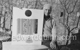 Max Ernst in the garden of her house at Seillans 1966. He holds the painting Schmetterling-Steuerzahler (papillon contribuable), for which he has used a piece of wallpaper, a flybat and a note from the income tax officer concerning his income tax return. - Photo by Edward Quinn