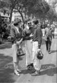 Ron Flockhart and Tony Brooks. Pina, Tony Brooks' Italian wife, carries an extra helmet and goggles for her husband. Monaco Grand Prix 1959. - Photo by Edward Quinn