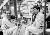 Smiling joking Innes Ireland, here wearing a false nose and glasses amuses fellow drivers John Surtees and Alan Stacey. Monaco Grand Prix 1960. - Photo by Edward Quinn