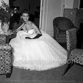 Sophia Loren in her Carlton Hotel room during the Cannes Film Festival wearing an evening gown designed by Emilio Schuberth, 27 April 1955. - Photo by Edward Quinn