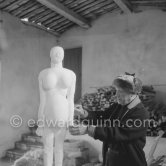 Pablo Picasso working on a plaster sculpture, La femme enceinte". In winter, Pablo Picasso wore warm clothes inside the studio, as heating was minimized to prevent the sculptures from. drying too quickly. In his studio Le Fournas, Vallauris 1953. - Photo by Edward Quinn