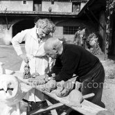 Pablo Picasso with some of the ceramic figures he made in clay, before they are put in the kiln. With him is Suzanne Ramié of the Madoura pottery. Suzanne is wearing a pendant by Pablo Picasso. Outside Madoura pottery, Vallauris 1953 - Photo by Edward Quinn