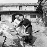 Pablo Picasso with some of the ceramic figures he made in clay, before they are put in the kiln. With him is Suzanne Ramié of the Madoura pottery. Suzanne is wearing a pendant by Pablo Picasso. Outside Madoura pottery, Vallauris 1953. - Photo by Edward Quinn