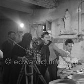 During filming of "Pablo Picasso", director Luciano Emmer, cameraman Giulio Gianini. Pablo Picasso behind the camera. With a statue of St-Claude Picasso, the patron saint of the potters, whose name was given to his younger son. Madoura pottery, Vallauris 14.10.1953. - Photo by Edward Quinn