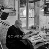 Pablo Picasso using a sharp instrument to scrape the surface of a clay plate as he designs a portrait. During filming of "Pablo Picasso", director Luciano Emmer, (left) and Pablo Picasso. Madoura pottery, Vallauris 14.10.1953. - Photo by Edward Quinn