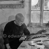 Pablo Picasso using a sharp instrument to scrape the surface of a clay plate as he designs a portrait. During filming of "Pablo Picasso", director Luciano Emmer, (left) and Pablo Picasso. Madoura pottery, Vallauris 14.10.1953. - Photo by Edward Quinn