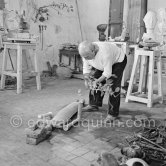 Pablo Picasso working in his sculpture studio Le Fournas making a sculpture figure with odds and ends from his scrap heap. Here he is adding a branch to the sculpture which was later replaced by a key. The finished sculpture got the name "La femme à la clé (La Taulière)" ("Woman with a key"). Le Fournas, Vallauris 1953. - Photo by Edward Quinn