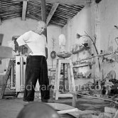 Pablo Picasso working in his sculpture studio Le Fournas making a sculpture figure with odds and ends from his scrap heap. Here he is adding a branch to the sculpture which was later replaced by a key. The finished sculpture got the name "La femme à la clé (La Taulière)" ("Woman with a key"). Le Fournas, Vallauris 1953. - Photo by Edward Quinn