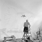Pablo Picasso working on the "War and Peace study" drawings on the wall of Chapelle de la Paix (or Temple de la Paix) for the documentary film of Luciano Emmer. (The panels of War and Peace of 1952 were away on exhibition). Vallauris 1953. - Photo by Edward Quinn