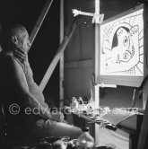 During filming of "Le mystère Picasso". Pablo Picasso working on "Tête de femme" with colored ink. He had a frame constructed on which he could stretch a transluscent piece of paper. He drew on one side, and the camera filmed the drawing being born from the other side. Nice, Studios de la Victorine 1955. - Photo by Edward Quinn