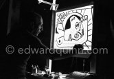 During filming of "Le mystère Picasso". Pablo Picasso working on "Tête de femme" with colored ink. He had a frame constructed on which he could stretch a transluscent piece of paper. He drew on one side, and the camera filmed the drawing being born from the other side. Nice, Studios de la Victorine 1955. - Photo by Edward Quinn