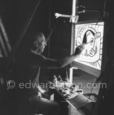 During filming of "Le mystère Picasso". Pablo Picasso working on "Tête de femme" with colored ink. He had a frame constructed on which he could stretch a transluscent piece of paper. He drew on one side, and the camera filmed the drawing being born from the other side. Nice, Studios de la Victorine 1955. - Photo by Edward Quinn