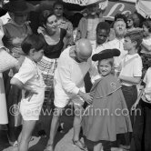 Pablo Picasso dresses up his children Paloma Picasso and Claude Picasso in miniature toreador costumes. Maya Picasso on the left, photographer Jacques-Henri Lartigue in the background with hat, his wife Florette. In front of restaurant Le Vallauris. Vallauris 1955. - Photo by Edward Quinn