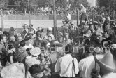 At Pablo Picasso's arrival on the village square where the corrida is to be held the band blares out some of his favourite Spanish melodies. Pablo Picasso in the crowd surrounded by his family and friends. Vallauris 1955. - Photo by Edward Quinn