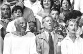 On the grandstand of a bullfight put on in Pablo Picasso's honor. From left: Jacqueline, Pablo Picasso, Jean Cocteau. Behind them Maya Picasso, Claude Picasso and Gérard Sassier. Vallauris 1955. - Photo by Edward Quinn