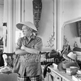 To strike a pose, Pablo Picasso tries on hats from his collection for his own amusement and that of his guests. La Californie, Cannes 1956. - Photo by Edward Quinn