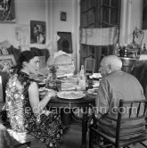 Pablo Picasso and Jacqueline. Luncheon at the dining and work table. Jacqueline is wearing a dress with printed motifs of a Pablo Picasso work. La Californie, Cannes 1956. - Photo by Edward Quinn