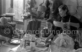 Pablo Picasso, Jacqueline and the cook. Luncheon at the dining and work table. Jacqueline is wearing a dress with printed motifs of a Pablo Picasso work. La Californie, Cannes 1956. - Photo by Edward Quinn