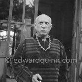 To enhance the effect of a new veluet blouse given him for his birthday, Pablo Picasso wears on of Jacqueline's necklaces and mimes what he imagines to be the appropriate expression for an ancient emperr. On the occasion of his 75th birthday on 25.10. La Californie, Cannes 1956. - Photo by Edward Quinn