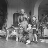 Pablo Picasso with Claude Picasso dressed up as a clown. Paloma Picasso is wearing the Davy Crockett outfit she received as a Christmas present.With goat Esmeralda. La Californie, Cannes 1956. - Photo by Edward Quinn