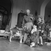 Pablo Picasso with Claude Picasso dressed up as a clown, Paloma Picasso is wearing the Davy Crockett outfit she received as a Christmas present. With goat Esmeralda. La Californie, Cannes 1956. - Photo by Edward Quinn