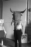 Pablo Picasso with a wicker bull mask originally intended for bullfighters' training, he becomes a living Minotaur. Beside him is a sculpture made of scrap wood with the features painted on it. La Californie, Cannes 1959. - Photo by Edward Quinn
