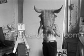Pablo Picasso with a wicker bull mask originally intended for bullfighters' training, he becomes a living Minotaur. Beside him is a sculpture made of scrap wood with the features painted on it. La Californie, Cannes 1959. - Photo by Edward Quinn
