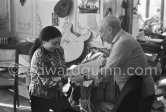 Pablo Picasso and Jacqueline opening a parcel with a new book with his works. Jacqueline is wearing a blouse made from a textile designed by Pablo Picasso. La Californie, Cannes, 1959. - Photo by Edward Quinn