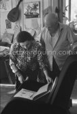 Pablo Picasso and Jacqueline viewing a new book with his works. Jacqueline is wearing a blouse made from a textile designed by Pablo Picasso. La Californie, Cannes 1959. - Photo by Edward Quinn