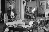 Pablo Picasso correcting "Faunes et chèvres". With Jacqueline (wearing a blouse with Pablo Picasso motifs). A pile of books Level, André: Souvenirs d'un colectionneur. Avec en frontispice un lithographie originale de Pablo Picasso (les saltimbanques). A.C. Mazo, Paris 15.10.1959. La Californie, Cannes 1959. - Photo by Edward Quinn