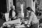 Pablo Picasso correcting "Faunes et chèvres". With Jacqueline (wearing a blouse with Pablo Picasso motifs). A pile of books Level, André: Souvenirs d'un colectionneur. Avec en frontispice un lithographie originale de Pablo Picasso (les saltimbanques). A.C. Mazo, Paris 15.10.1959. La Californie, Cannes 1961. - Photo by Edward Quinn