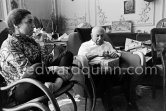 Pablo Picasso with his Easter present. Jacqueline, sitting in a rocking chair, is wearing a blouse made from a textile designed by Pablo Picasso. La Californie, Cannes 1961. - Photo by Edward Quinn