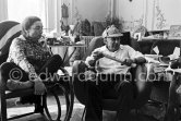 Pablo Picasso and Jacqueline. He never fails to surprise with the unusual, in this case a check dear-stalker worn with all the aplomb of a 19th century English Squire. Jacqueline, sitting in a rocking chair, is wearing a blouse made from a textile designed by Pablo Picasso. La Californie, Cannes 1961. - Photo by Edward Quinn