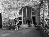 Jacqueline behind the window. Kaboul on the terrace in front of the entrance to Le Mas Notre Dame de Vie. Because this house also quickly became too small, Picasso had a room built onto the terrace. Le Mas Notre Dame de Vie, Mougins 1962. - Photo by Edward Quinn