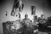 Behind Pablo Picasso a large sofa weighed down with an array of papers, prints, tennis rackets, hats. Mas Notre-Dame-de-Vie, Mougins 1964. - Photo by Edward Quinn