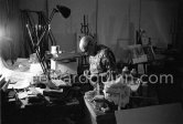 Pablo Picasso at work in a corner of his living room table, engraving his signature on a small lucky dollar coin at a visitor’s request. Visitors usually brought some object or present that they hoped would interest or intrigue Pablo Picasso, and they were seldom disappointed. Mas Notre-Dame-de-Vie, Mougins 1967. - Photo by Edward Quinn