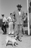 Edward Duke of Windsor and his dog at Nice Airport. The Duke came to the airport to fetch the Duchess of Windsor and then they drove on to the Carlton Hotel in Cannes. Some years before, the Duke and the Duchess had lived nearby at the Château de la Croe which later became the property of Mr. Onassis. In the gardens of the Château there still is a small tombstone in memory of their pet dog, inscribed "Preezie A 
Faithful Little Friend of Edward and Wallis. Duke and Duchess of Windsor". Nice 1954. - Photo by Edward Quinn