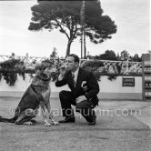 English comedian Norman Wisdom ready to share a treat with his German Shepherd Dog on the legendary Old Course Golf. Cannes 1955. - Photo by Edward Quinn